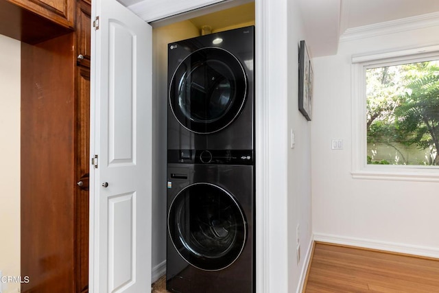 clothes washing area with stacked washer and clothes dryer, ornamental molding, and hardwood / wood-style floors