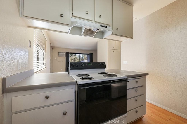 kitchen with baseboards, light wood-style floors, electric stove, a textured wall, and under cabinet range hood