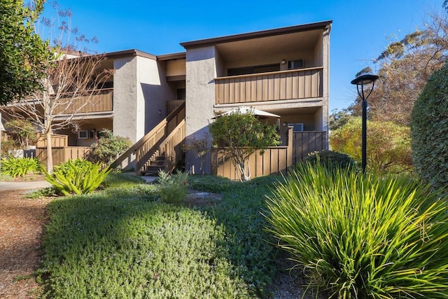 exterior space featuring a balcony, stairs, and stucco siding