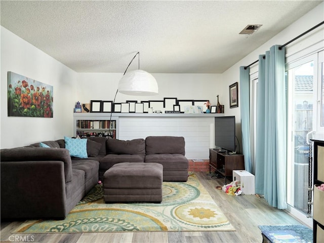 living room with light wood-type flooring and a textured ceiling