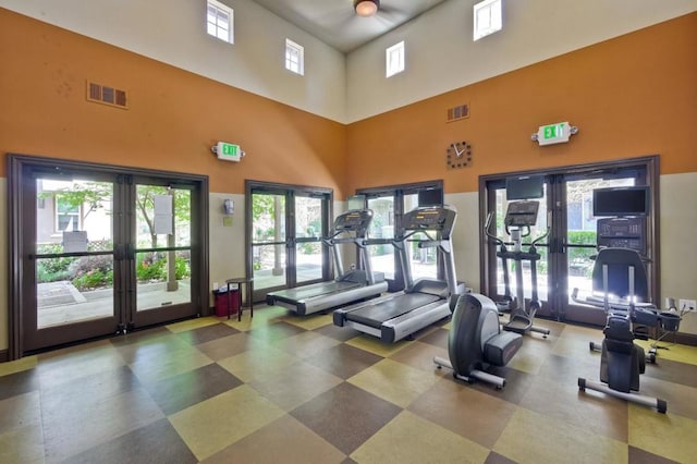 gym with a towering ceiling and french doors