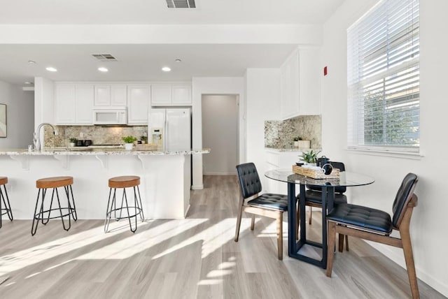 kitchen with white cabinets, white appliances, kitchen peninsula, and decorative backsplash