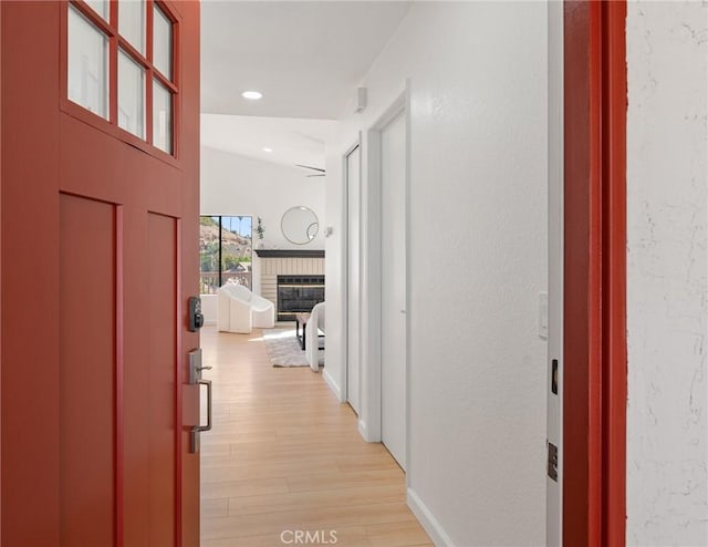 hall featuring recessed lighting, light wood-style flooring, baseboards, and a textured wall