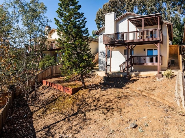 rear view of house with a deck, stucco siding, a chimney, and a fenced backyard