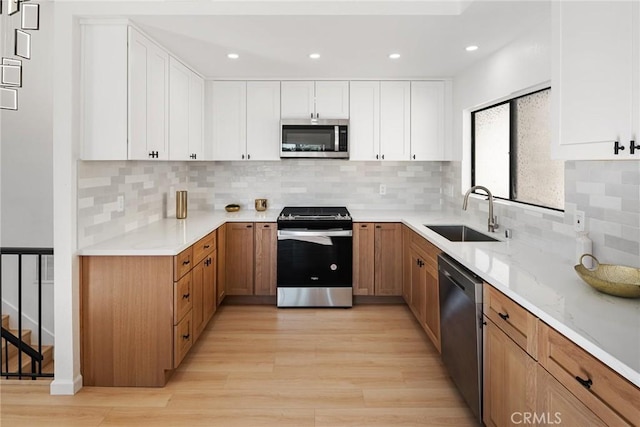 kitchen with a sink, stainless steel appliances, light wood-style floors, and white cabinets