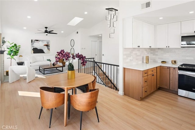 dining area featuring vaulted ceiling with skylight, light wood-style flooring, recessed lighting, and visible vents