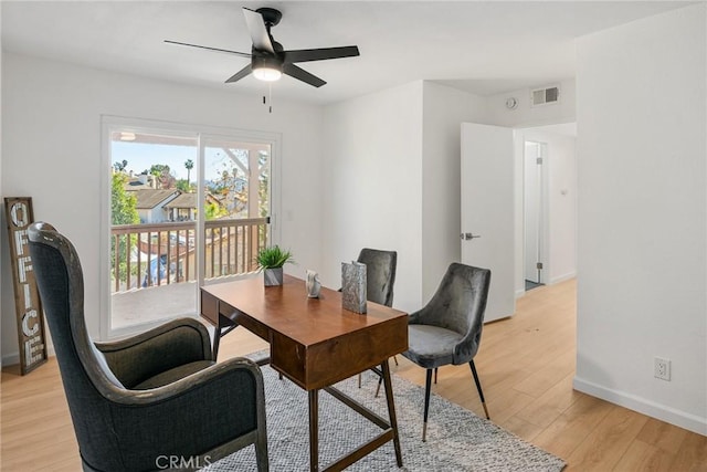 office space with visible vents, baseboards, a ceiling fan, and light wood finished floors