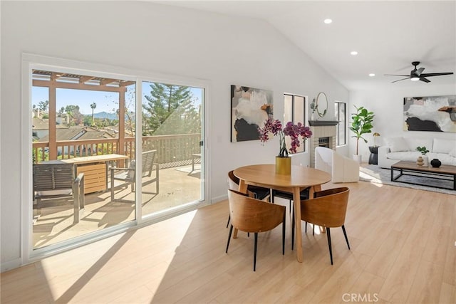 dining space featuring recessed lighting, light wood-style flooring, a fireplace, and lofted ceiling