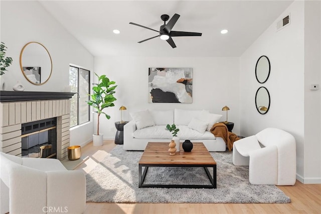 living area with visible vents, wood finished floors, recessed lighting, a fireplace, and vaulted ceiling