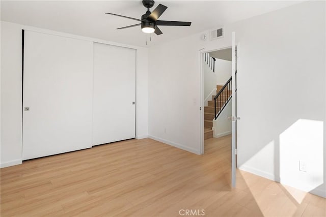 unfurnished bedroom featuring visible vents, baseboards, ceiling fan, light wood-style flooring, and a closet