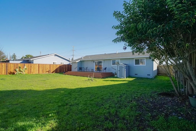 rear view of property with a deck, a yard, and a shed