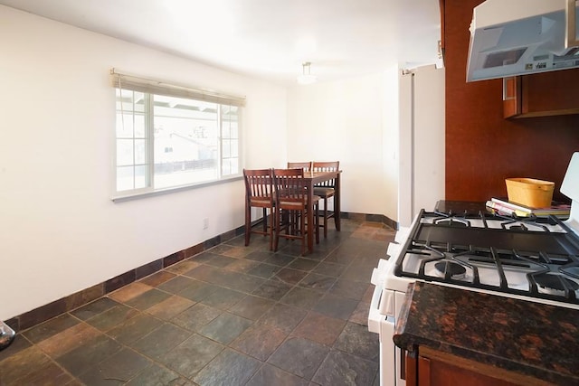 kitchen featuring white gas range and exhaust hood