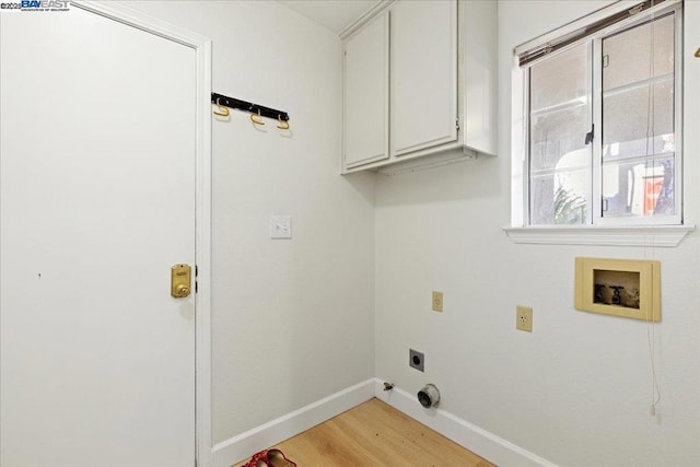 clothes washing area featuring electric dryer hookup, hookup for a washing machine, cabinets, and light hardwood / wood-style flooring