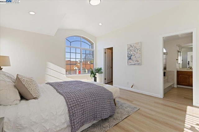 bedroom featuring lofted ceiling, ensuite bathroom, sink, and light hardwood / wood-style flooring