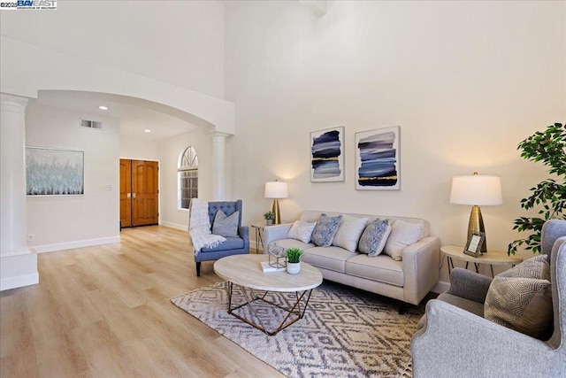 living room with light wood-type flooring and ornate columns