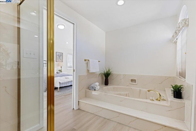 bathroom featuring tiled tub and hardwood / wood-style flooring