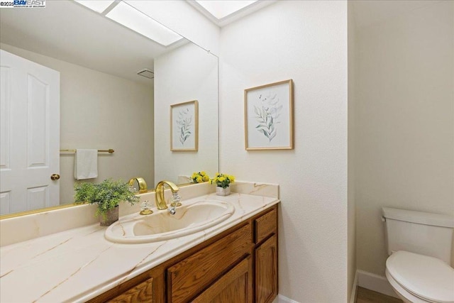 bathroom featuring a skylight, vanity, and toilet