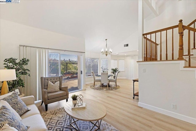 living room featuring high vaulted ceiling, a notable chandelier, and light hardwood / wood-style floors