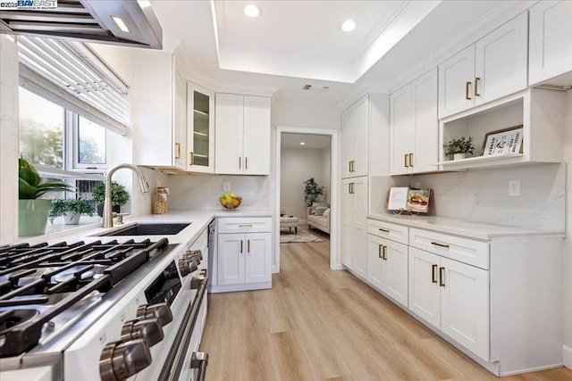 kitchen with sink, white cabinets, a raised ceiling, light hardwood / wood-style flooring, and gas range