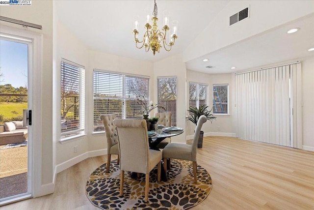 dining room with light wood-type flooring, lofted ceiling, and a chandelier