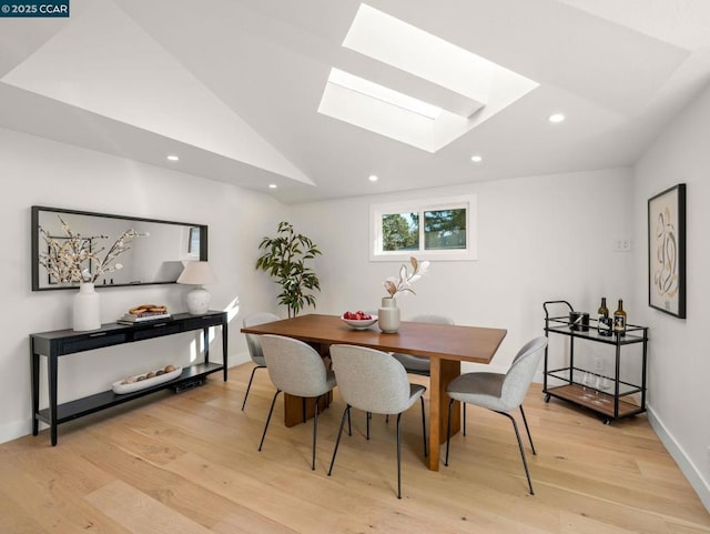 dining room featuring light hardwood / wood-style floors and lofted ceiling with skylight