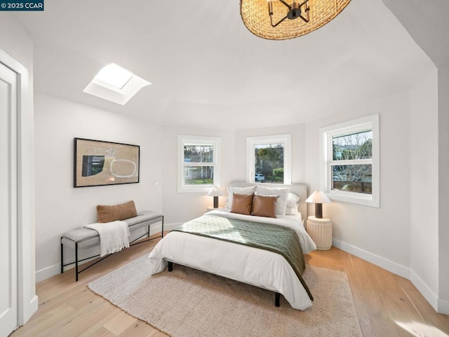 bedroom featuring light hardwood / wood-style flooring and a skylight