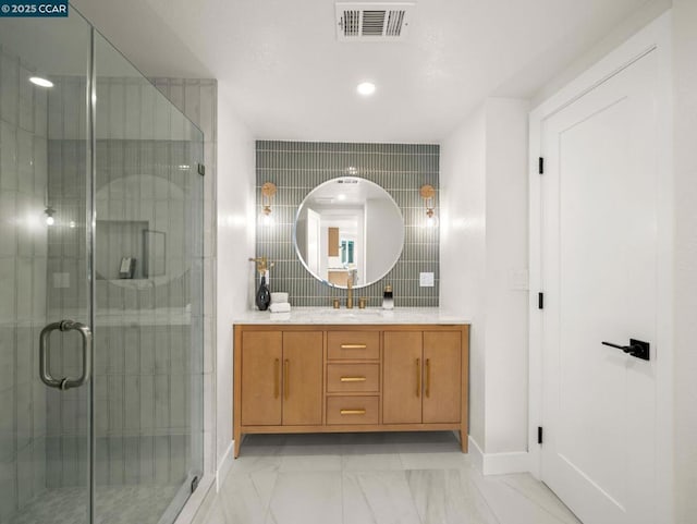 bathroom with a shower with door, vanity, and decorative backsplash