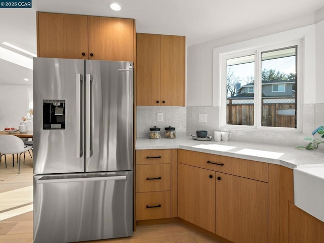 kitchen featuring light stone countertops, tasteful backsplash, and stainless steel fridge