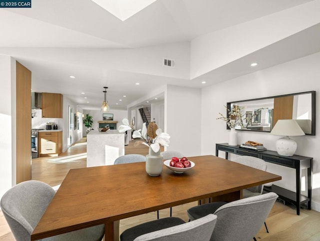 dining room featuring light hardwood / wood-style flooring and high vaulted ceiling