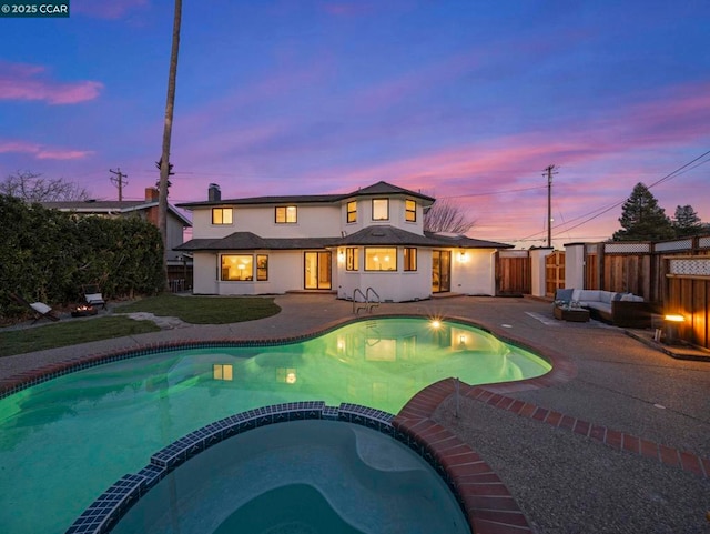 pool at dusk featuring a patio area and an outdoor living space