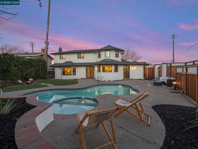 pool at dusk with a patio, an in ground hot tub, and an outdoor living space