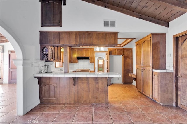 kitchen featuring wooden ceiling, tile countertops, light tile patterned floors, tasteful backsplash, and kitchen peninsula