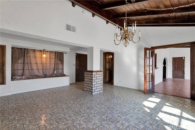 unfurnished living room featuring wood ceiling, high vaulted ceiling, beam ceiling, an inviting chandelier, and decorative columns