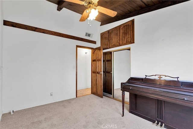 interior space featuring lofted ceiling with beams, light carpet, ceiling fan, and wooden ceiling