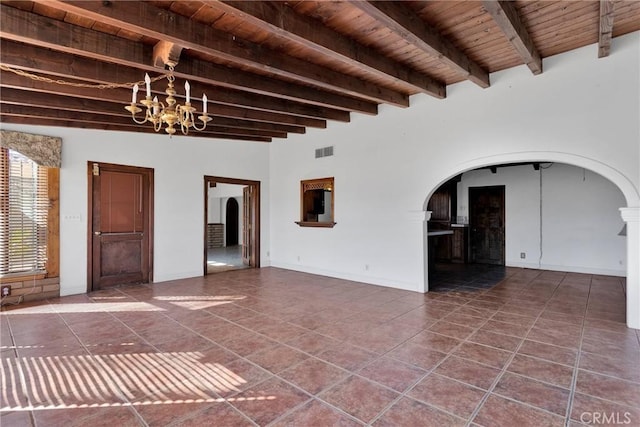 unfurnished living room featuring beam ceiling, a chandelier, dark tile patterned flooring, and wood ceiling