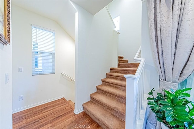 staircase featuring vaulted ceiling and hardwood / wood-style flooring