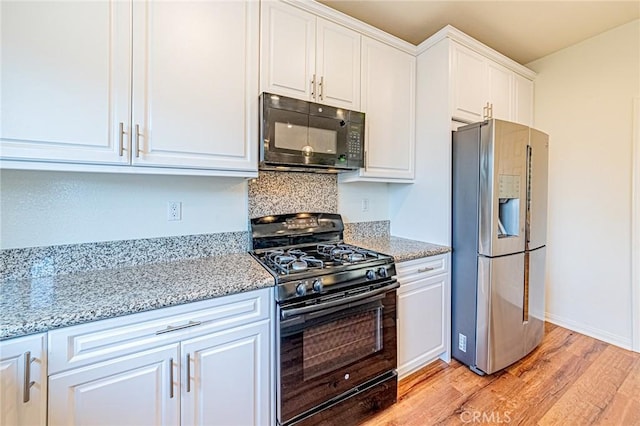 kitchen with black appliances, light wood-type flooring, white cabinets, and light stone countertops