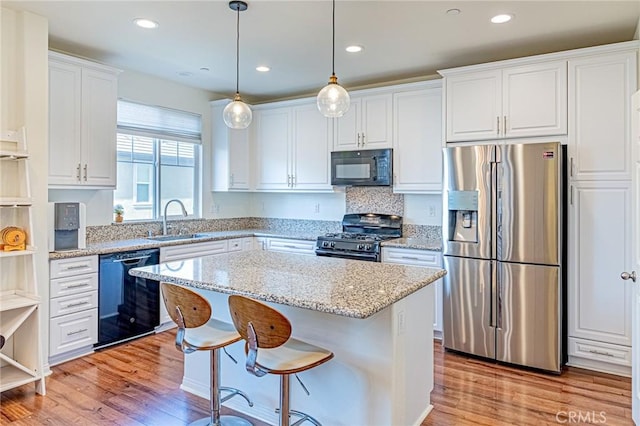 kitchen with black appliances, a center island, pendant lighting, white cabinets, and sink