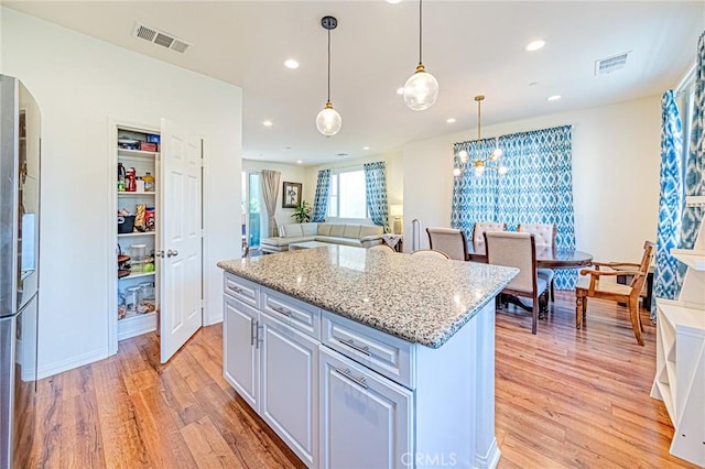 kitchen featuring light wood-type flooring, pendant lighting, and a center island