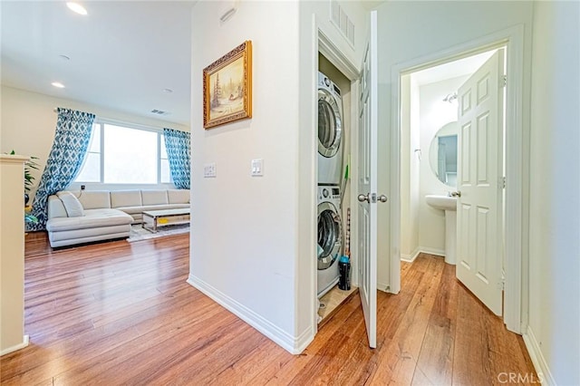 corridor featuring light wood-type flooring and stacked washer and dryer