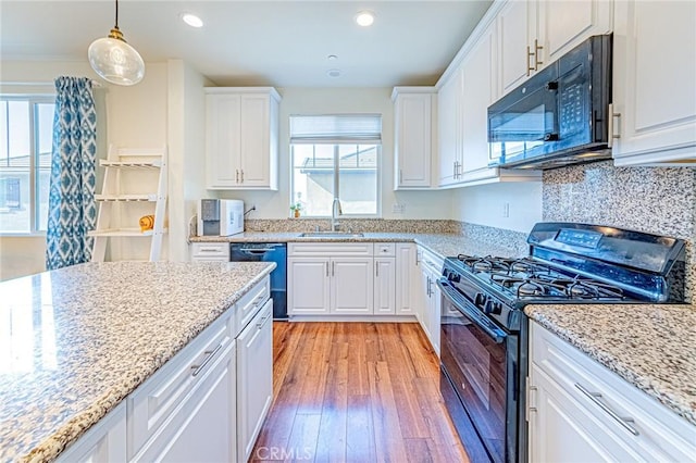 kitchen featuring black appliances, light hardwood / wood-style floors, pendant lighting, sink, and white cabinetry