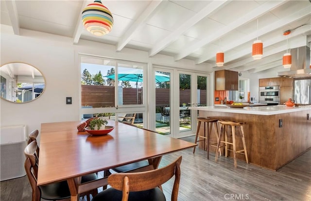 dining area with a healthy amount of sunlight, lofted ceiling with beams, and hardwood / wood-style flooring