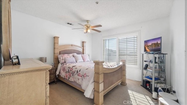 bedroom with a textured ceiling, light colored carpet, and ceiling fan