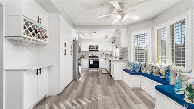 hallway with sink, a raised ceiling, a textured ceiling, and light hardwood / wood-style floors