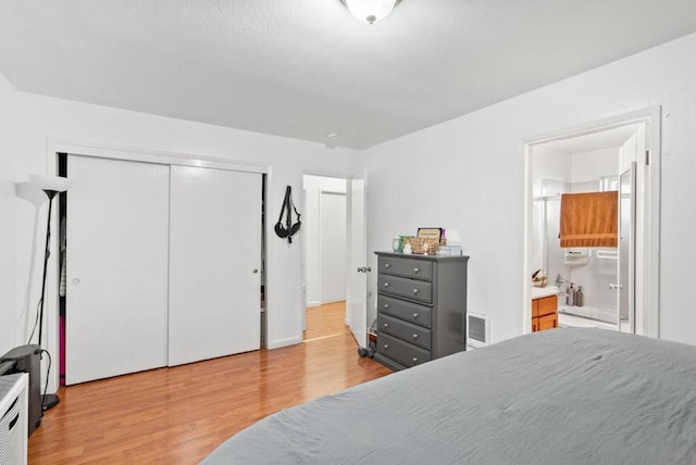 bedroom featuring light hardwood / wood-style flooring, a closet, and ensuite bathroom