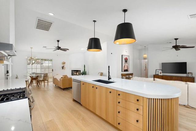 kitchen featuring appliances with stainless steel finishes, light wood-type flooring, decorative light fixtures, and sink