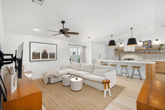 living room featuring sink, ceiling fan, and light hardwood / wood-style floors