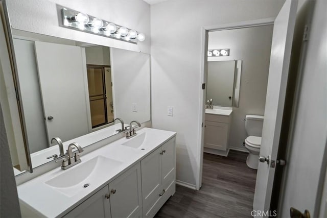 bathroom with toilet, wood-type flooring, and vanity