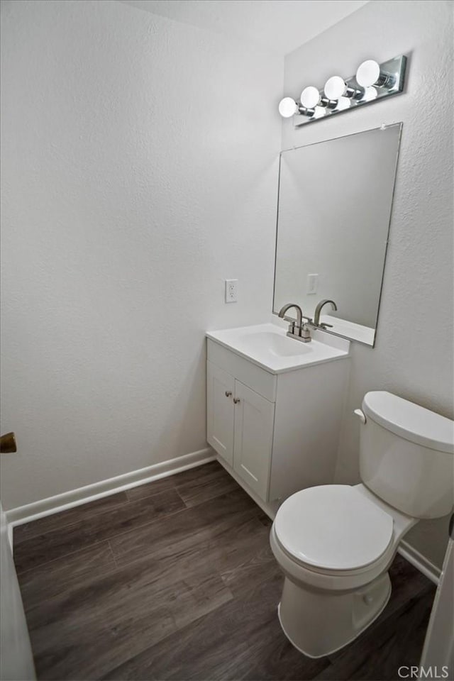 bathroom with toilet, vanity, and hardwood / wood-style floors