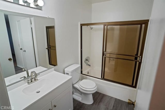 full bathroom with vanity, wood-type flooring, shower / bath combination with glass door, and toilet